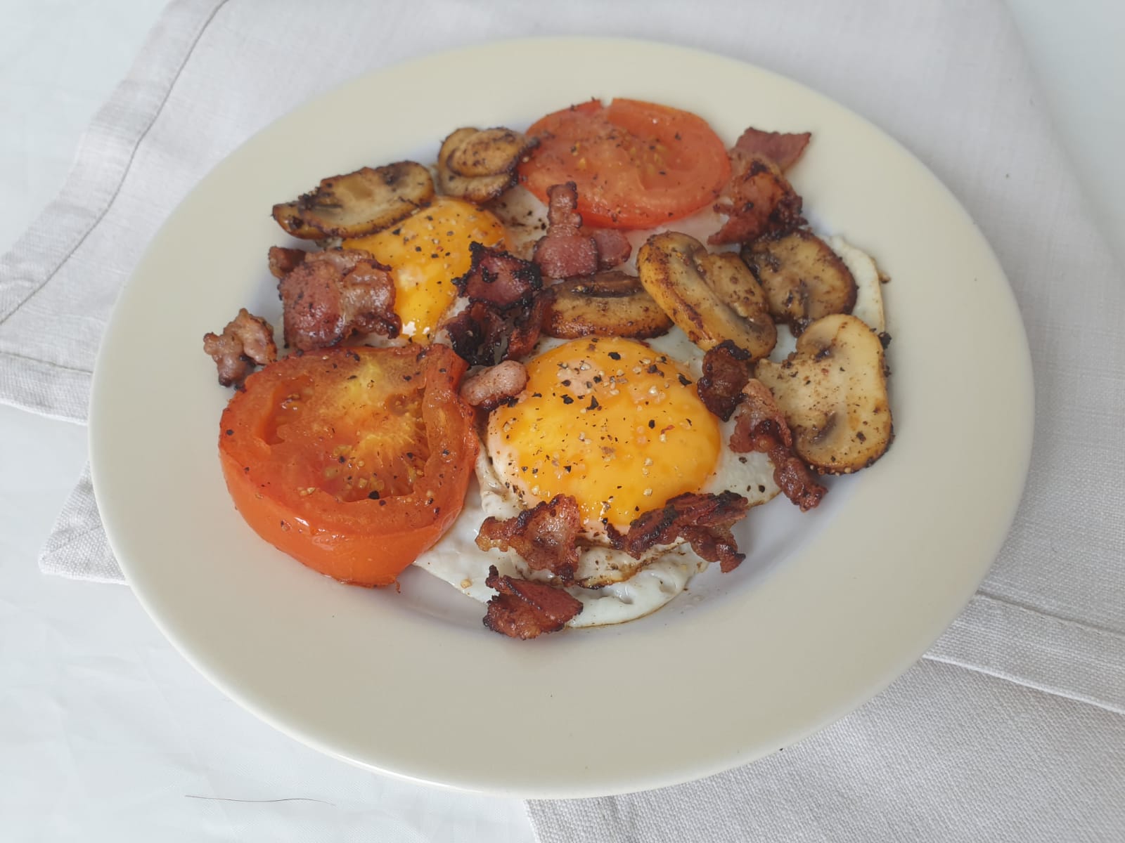 Gebakken eieren met tomaat, spek en champignons