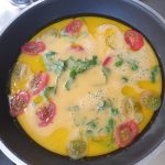 Schenk het eier beslag over de tomaatjes heen in de koekenpan