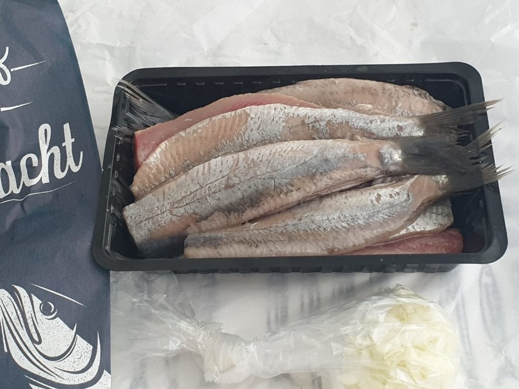 Haring met uitjes in plastic bakje van viskraam