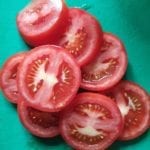 Groene snijplank met in plakjes gesneden tomaat.