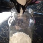 Yoghurt met een flessenschraper in een glazen pot doen