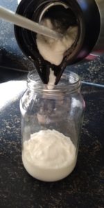 Yoghurt met een flessenschraper in een glazen pot doen