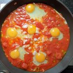 Breek de eieren voorzichtig in de tomatensaus