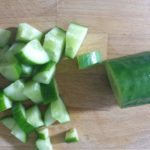 Houten snijplank met stukjes komkommer