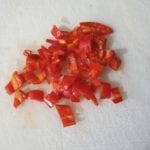 Witte snijplank met in stukjes gesneden chili peper