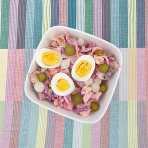 Witte schaal haringsalade gegarneerd met hardgekookt ei