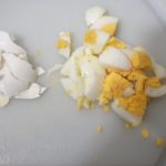 Witte snijplank met in stukjes gesneden hardgekookt ei