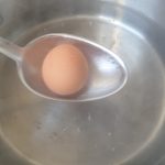 De eieren één voor één in de pan met kokend water leggen.