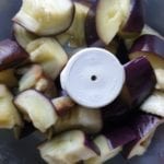 Doe de aubergine blokjes in de kleine kom van een keukenmachine
