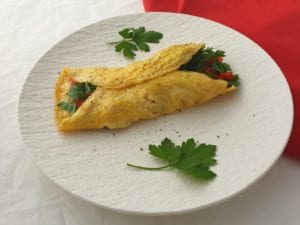 Wit bord met dubbelgevouwen omelet gevuld met groenten