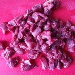 Rode snijplank met in stukjes gesneden vlees