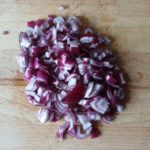 Houten snijplank met in stukjes gesneden rode ui