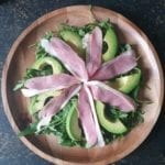Houten bord met rucola, avocado en gerookte eend