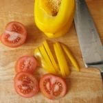 Houten snijplank met plakjes tomaat en reepjes paprika