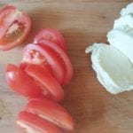 Houten snijplank met plakken tomaat en mozzarella
