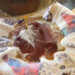 Ghee in een zeef met daarop een gevouwen theedoek